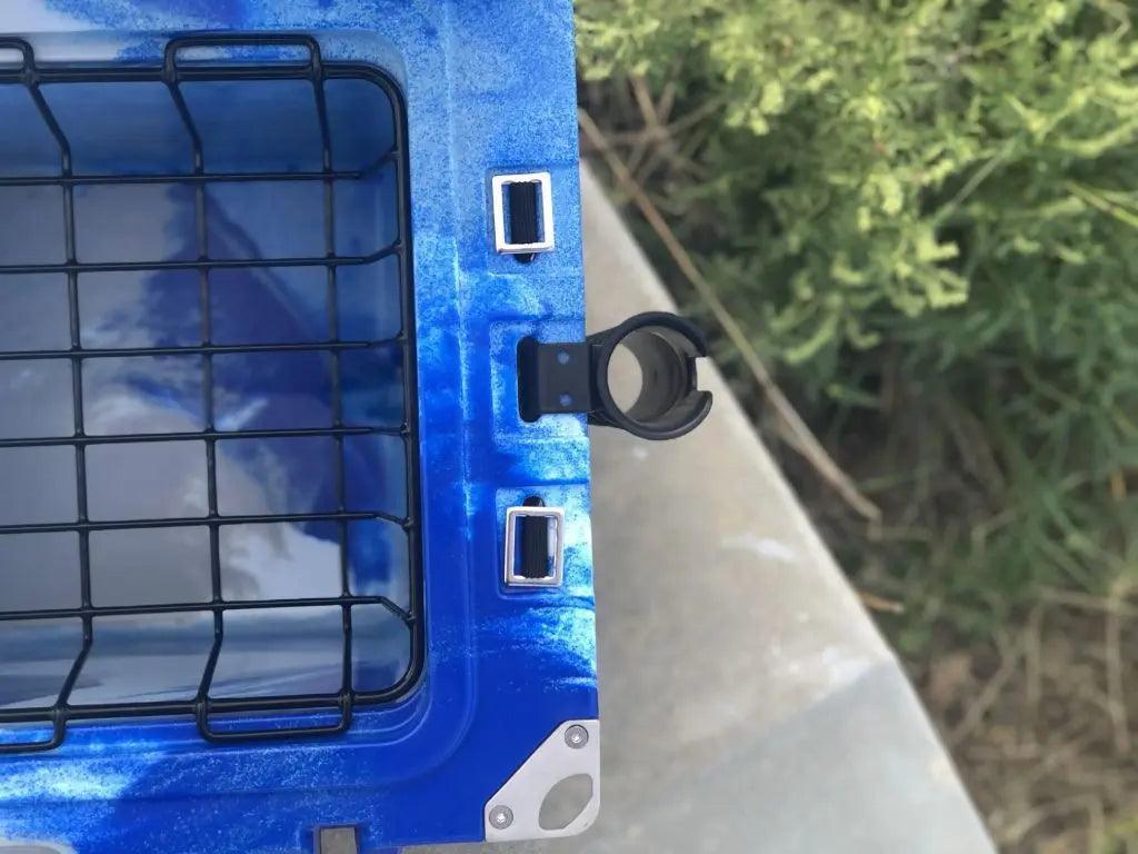 Close-up of blue Iceland Cooler with mounted rod holder and interior wire basket, ideal for hands-free fishing and outdoor storage.