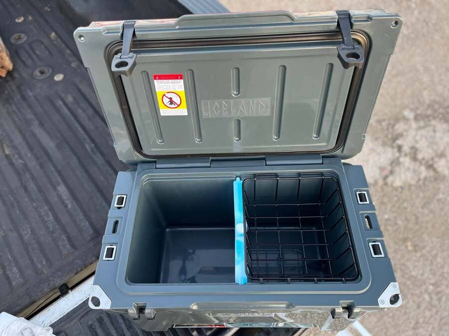 Open Iceland Cooler with Glacier Ice Pack and removable wire basket, shown on truck bed for outdoor use.