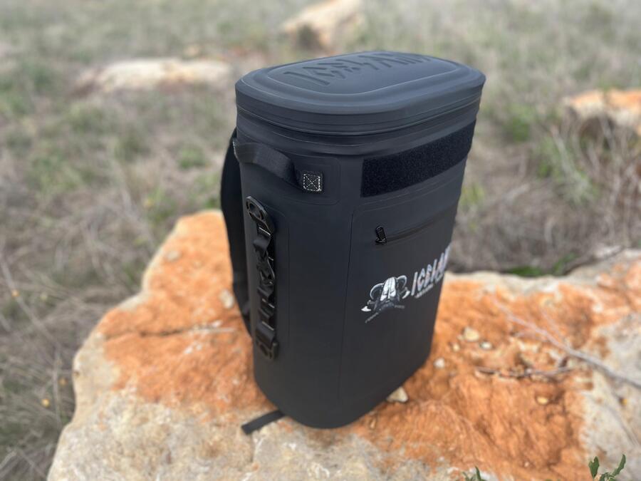 Black Iceland Coolers Saga Series 30-can soft cooler backpack resting on a large rock in an outdoor field