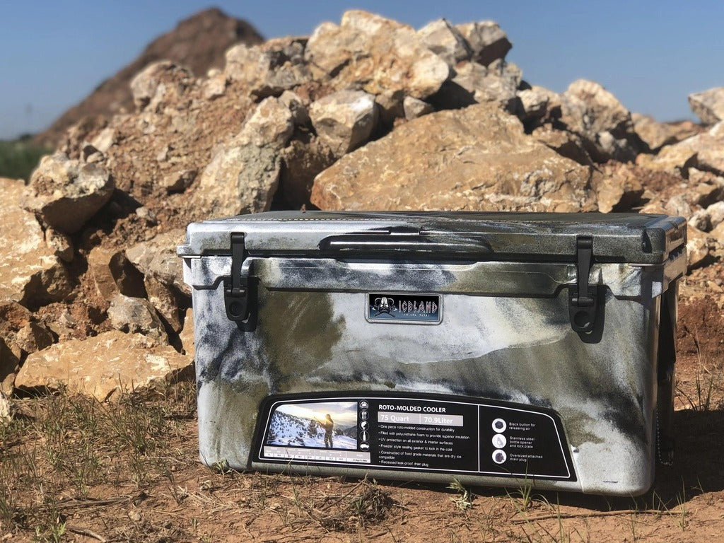 Iceland Coolers Viking Series 75 QT in arctic camo, shown outdoors on rocky terrain with dual-latch front and product label visible.