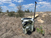 Iceland Coolers 7.5-gal camo cooler with wheels and handle, shown in dry, grassy terrain—built for mobility, hunting, and rugged use.