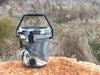 Iceland Coolers 5-gal marbled bucket cooler with spout and carry handle, sitting on a rock in dry grass—rugged, rotomolded design.