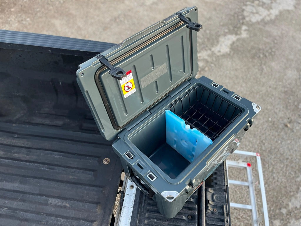 Open gray Iceland Cooler with Glacier Ice Pack and basket inside, shown on a truck bed ready for outdoor use.