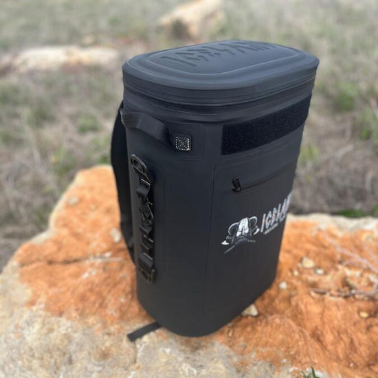 Black Iceland Coolers Saga Series 30-can soft cooler backpack resting on a large rock in an outdoor field